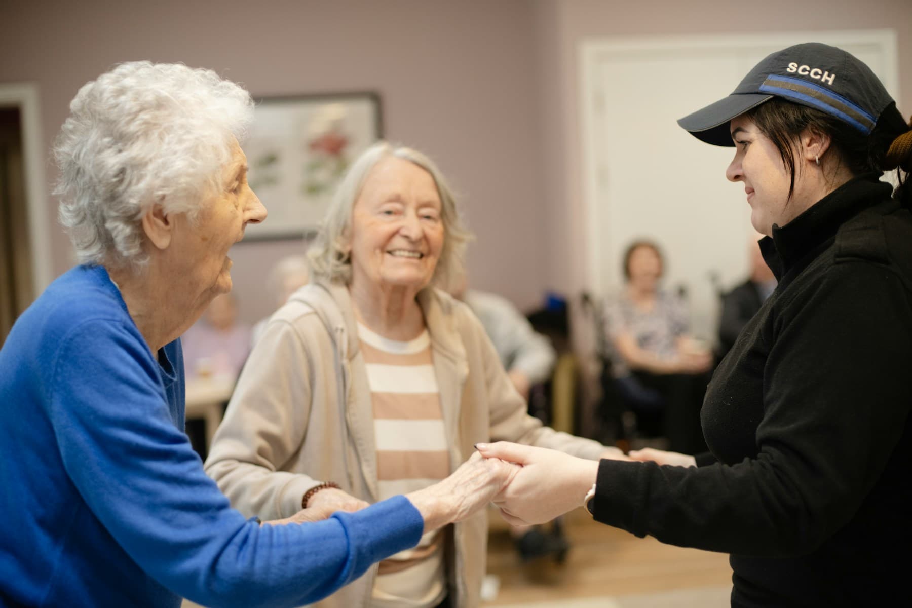 A care worker holding the hands of older adults during a care activity.